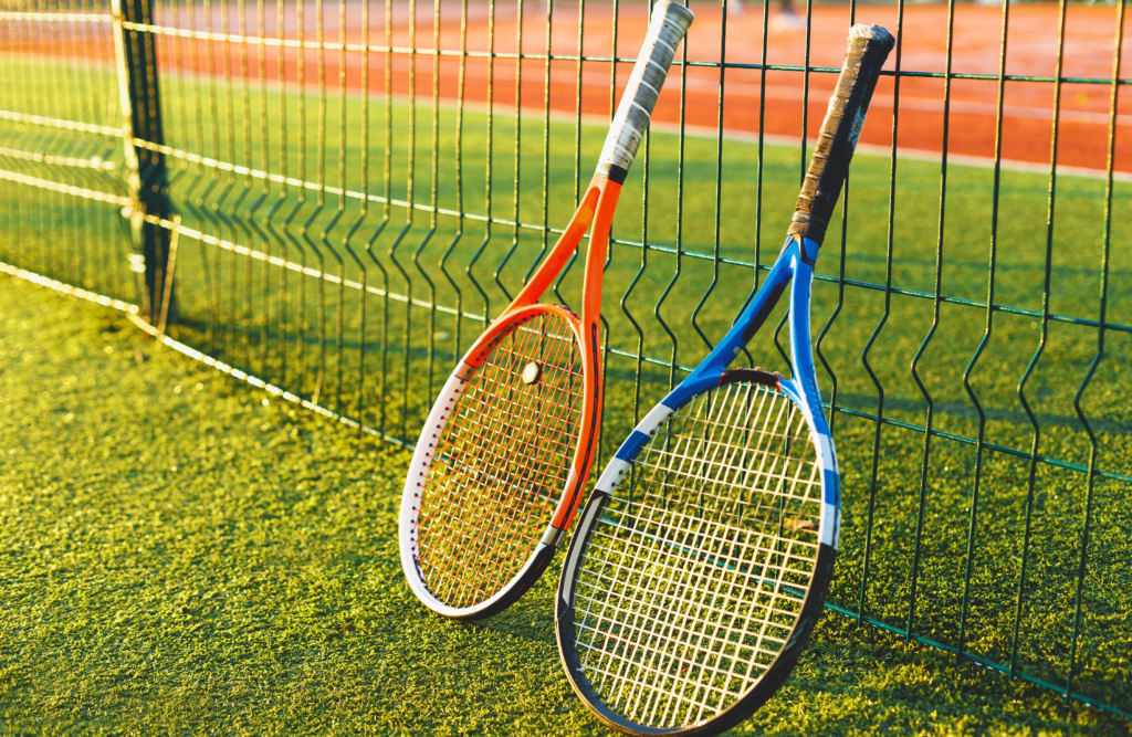 ClubU, Club con Pádel y Tenis Santa Magdalena de Pulpis. Un par de raquetas, una azul y una naranja, apoyadas sobre una valla de hierro.