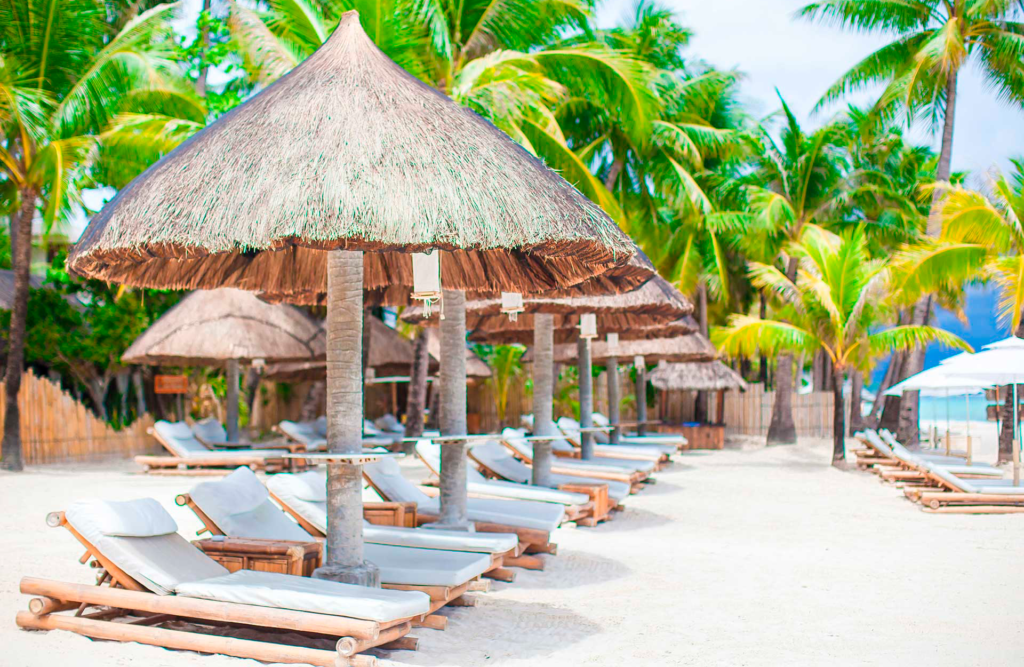 ClubU, Tu Club Exclusivo de Ocio y Deporte Santa Magdalena de Pulpis. Tumbonas de madera con sombrillas de madera en la playa.