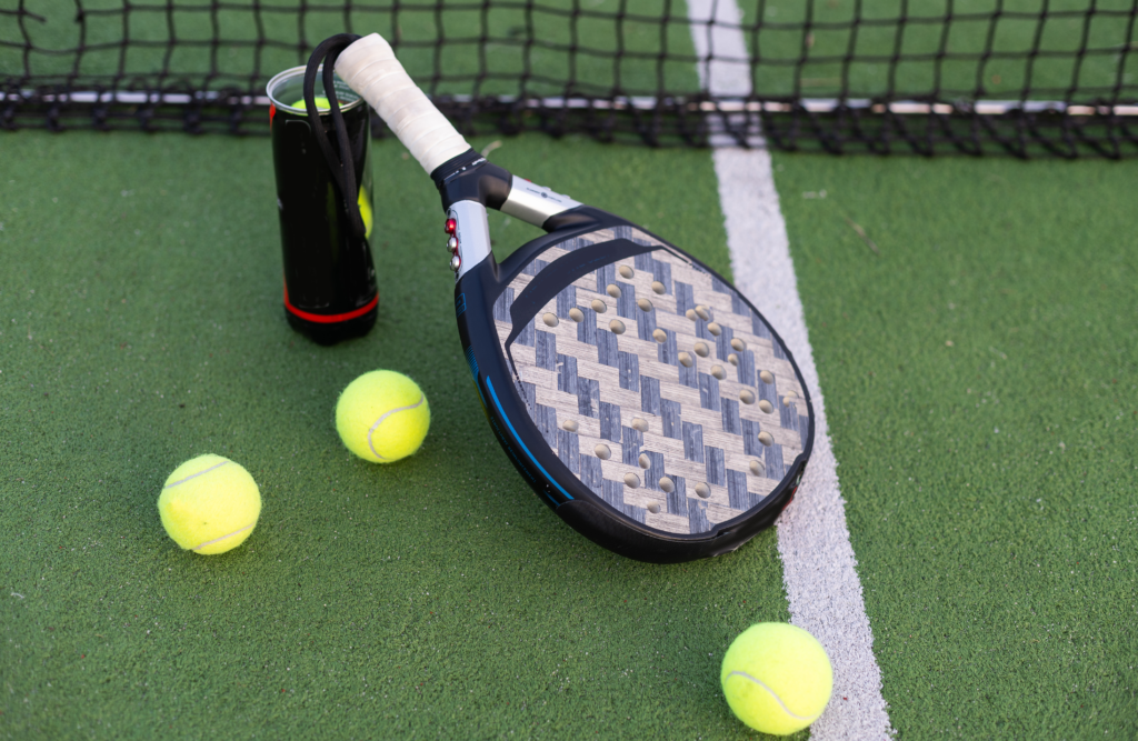 ClubU, Tu Club Exclusivo de Ocio y Deporte Vinaròs. Pala de pádel apoyada en un envase para pelotas de tenis junto a sus 3 pelotas.
